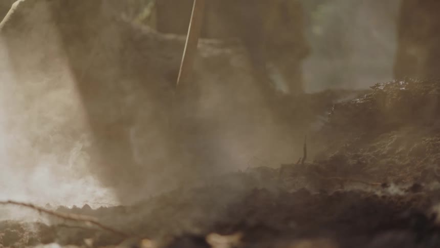 A person is moving soil over a fire