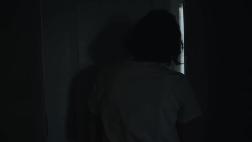 A silhouette of a woman walking up stairs carrying something walking into a room then setting the object down and running back out