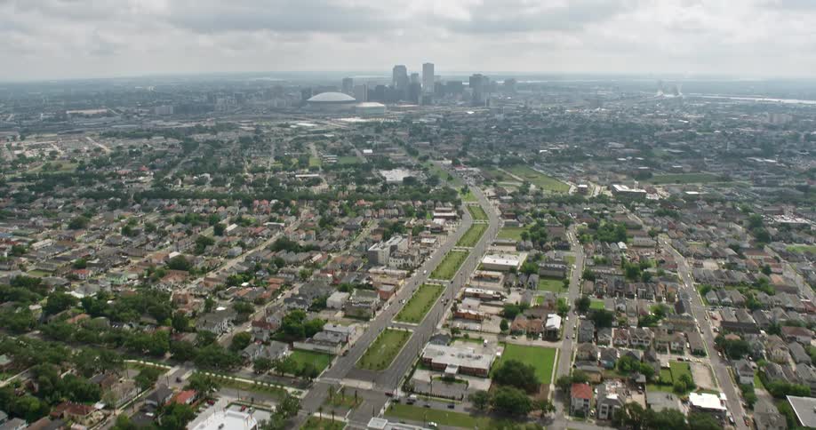 A breathtaking 4K aerial footage of New Orleans Louisiana revealing the downtown skyline from the Garden District suburbs with partly cloudy skies and tilt-up shot