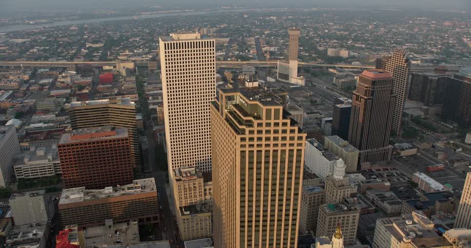 An epic 4K aerial tilt from French Quarter to Downtown New Orleans at sunrise over partly cloudy skies revealing a breathtaking metropolitan area with impressive supertalls and skyscrapers
