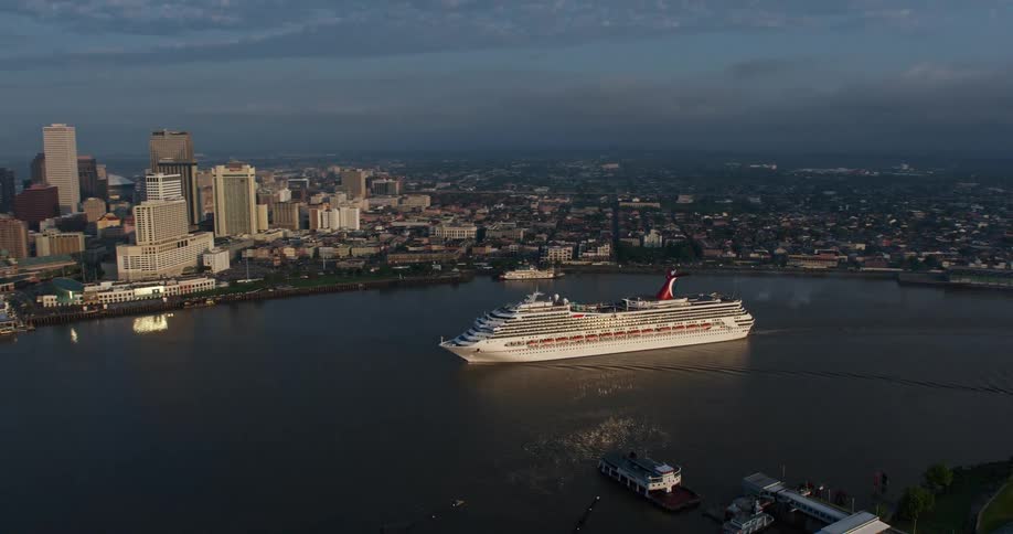A stunning 4K aerial shot of a Carnival Cruise ship on the Mississippi river revealing Downtown New Orleans at sunrise during summer