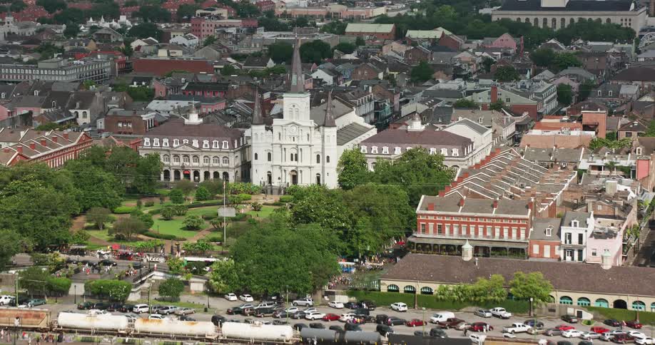 An aerial 4K video fly over of St Louis Cathedral and Jackson Square in the French Quarter New Orleans Louisiana on a partly cloudy day showcasing a famous historical landmark and place of worship