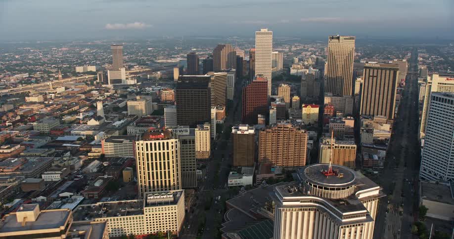 An aerial flyover of the Mississippi River at sunrise approaching downtown New Orleans towering skyscrapers and high rise buildings