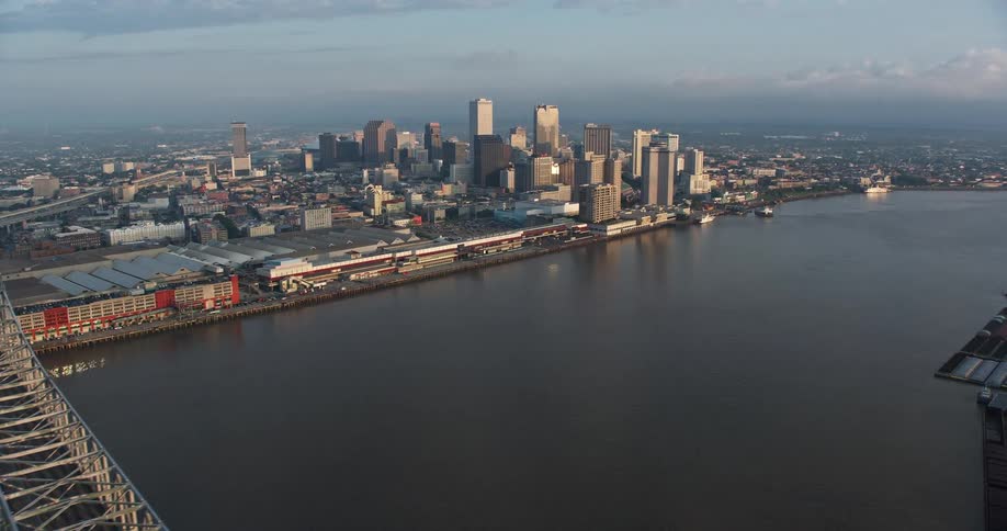 An aerial shot of the Crescent City Connection bridge at sunrise with the city of Downtown New Orleans in the background showcasing the city skyline and waterways