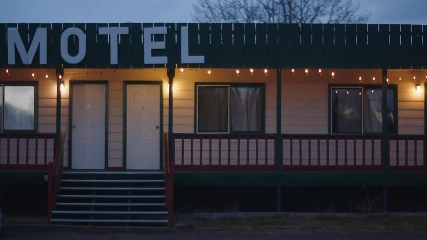 The front of a motel is lit by porch lights at dusk