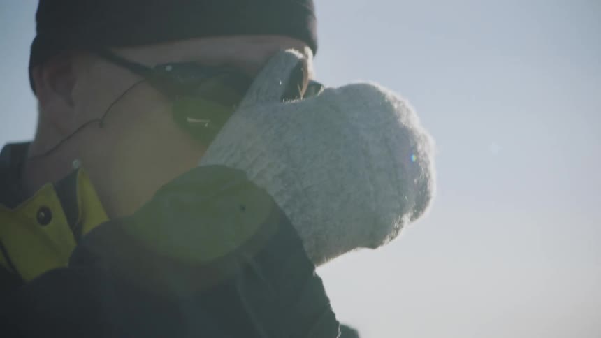 A man is standing outdoors and wearing gloves