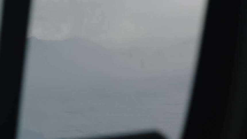 Man standing on a snow field seen from the window of a helicopter taking off