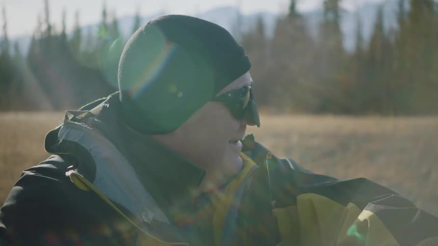 Man wearing goggles and nose cover prepares to hike in the mountains at morning
