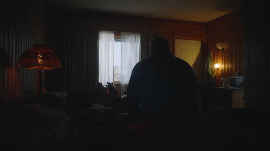 A man is standing in a room with the lights off