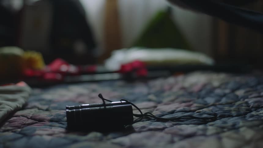 A close up of a person unfolding binoculars on a bed surface removing the wrap and setting the binoculars on the bed