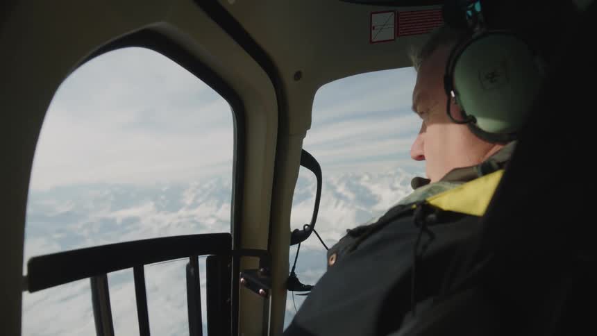Pilot flies aircraft over snowy mountains while talking on headset
