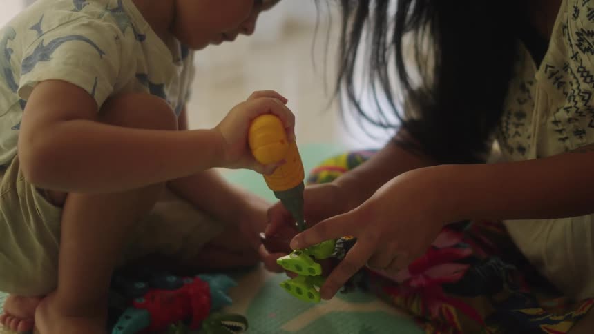 A mother and son play with toys together