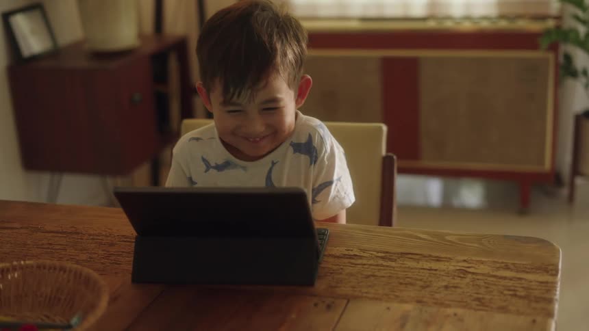 A young boy happily watching something on a tablet