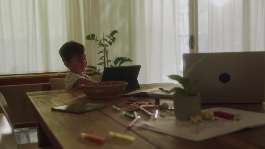 A young boy watches something on a tablet