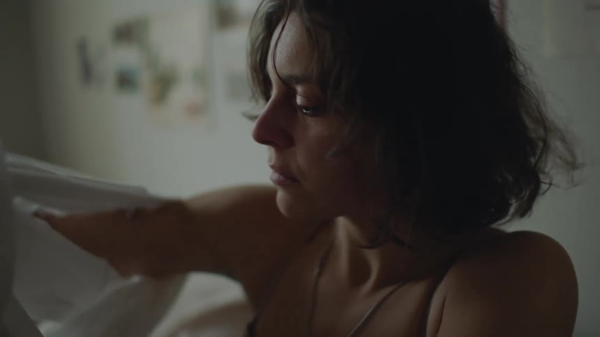 Young stressed woman sitting at bed sad or scared puts on a white shirt