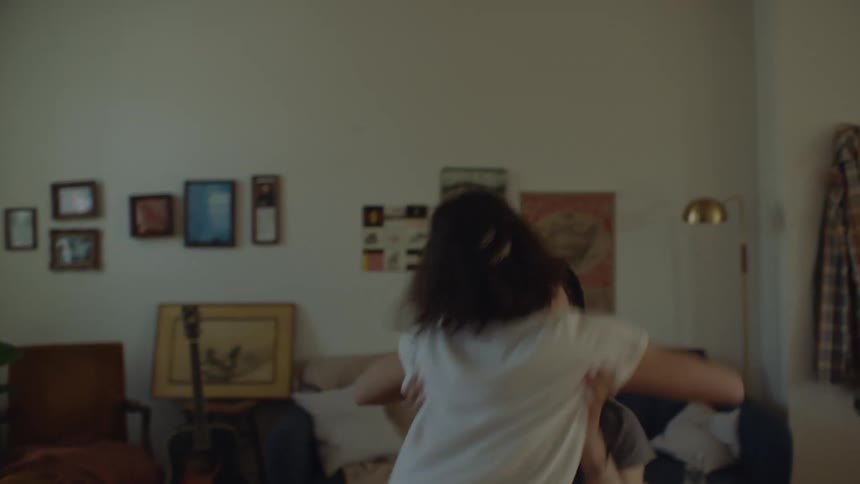 A man and woman hugging and then breaking into a dance then the man storms up stairs