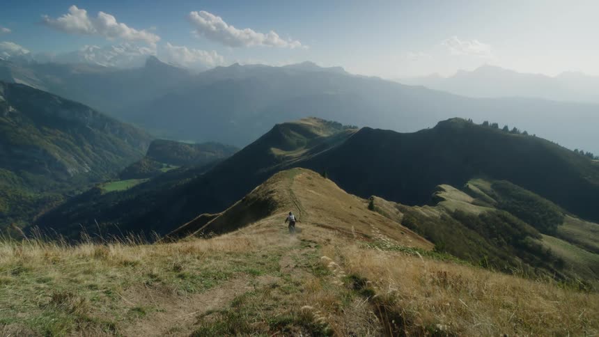 Man rides a mountain bike at full speed down hill on a mountain ridge at morning