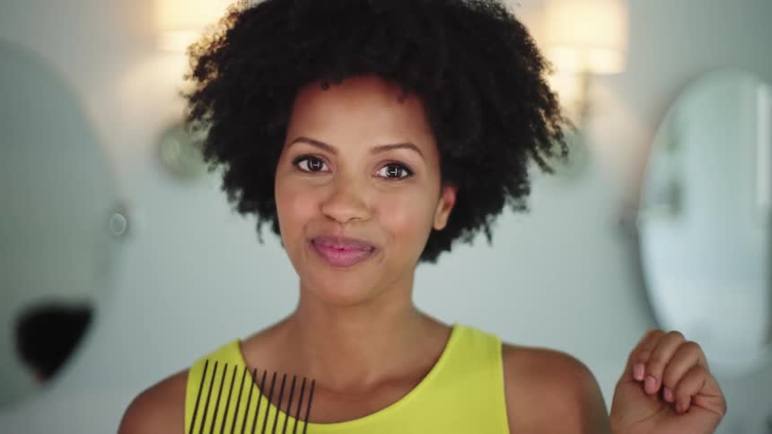 Pretty black woman styling her hair with a pick