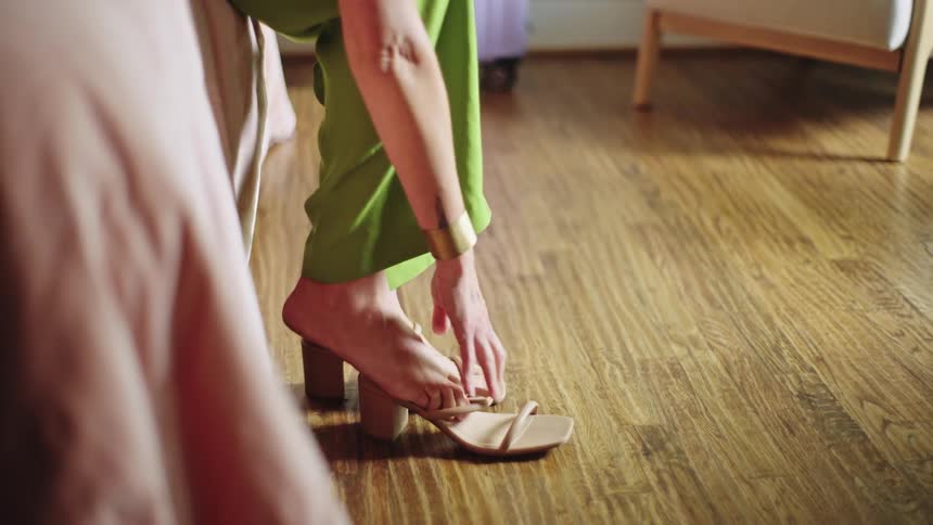 Woman sitting in the bed puts on heeled sandals and walks away