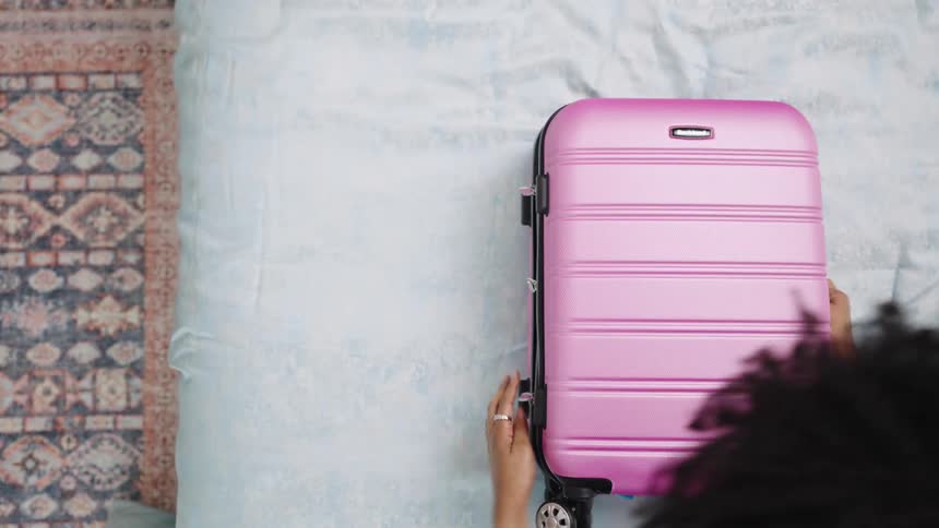 A female is packing clothes in her suitcase