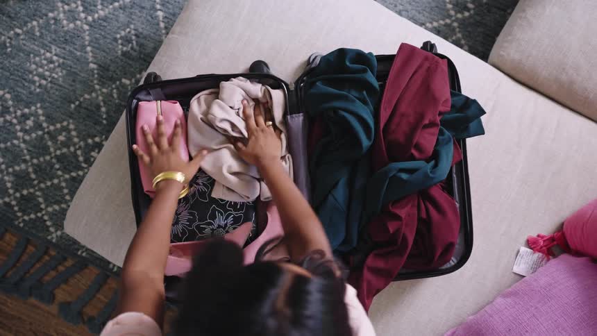 Woman with pink t shirt packs a suitcase