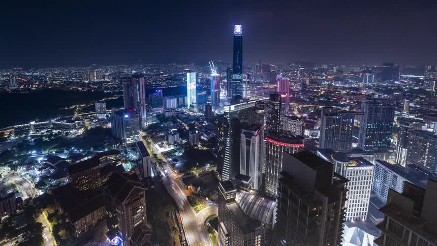 Cars drive through a maze of endless skyscrapers in Kuala Lumpur at night