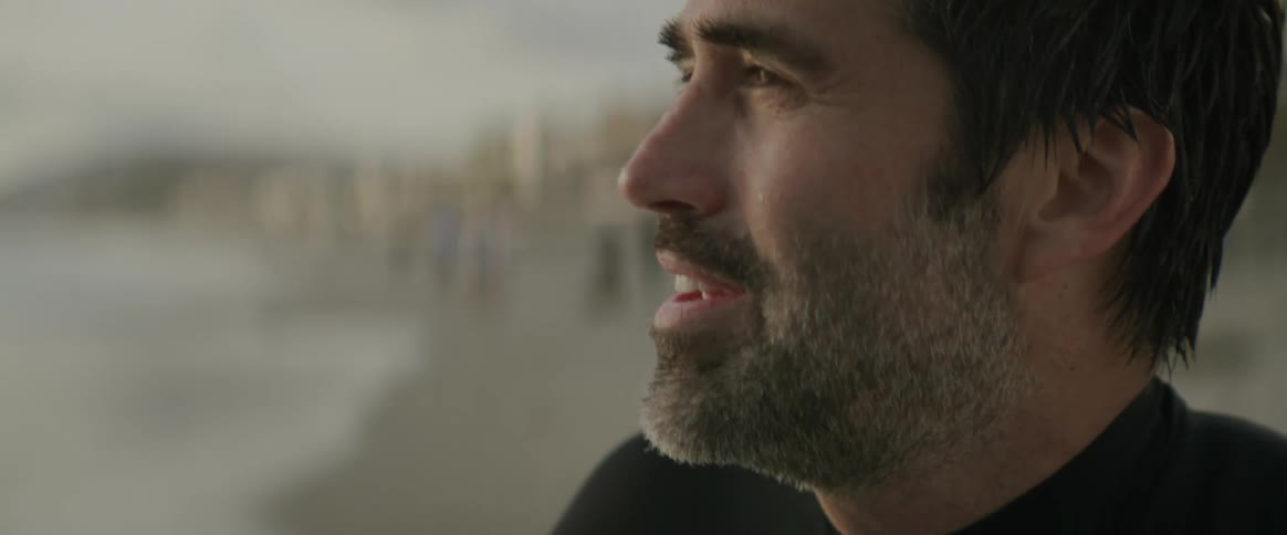 A man is talking and sitting on the beach