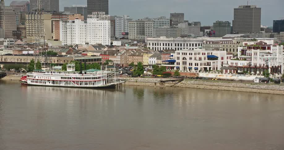 4K aerial footage of Steamboat Natchez cruising along the French Quarter riverfront in New Orleans Louisiana on a partly cloudy day