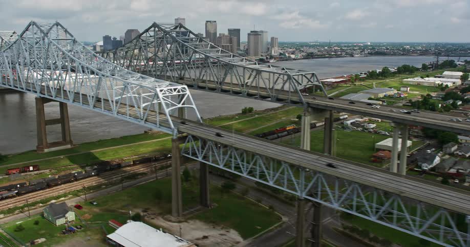 A 4K aerial view of two bridges crossing the Mississippi river and revealing the downtown New Orleans skyline on a cloudy day