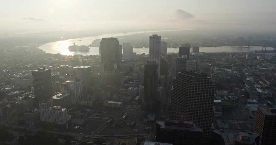 A stunning 4K aerial footage reveals the Superdome in Downtown New Orleans at sunrise as the camera tilts up showcasing the high-rise buildings and waterways of the Louisiana city