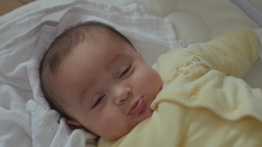 Video portrait of a baby resting in bed at home looking at the camera