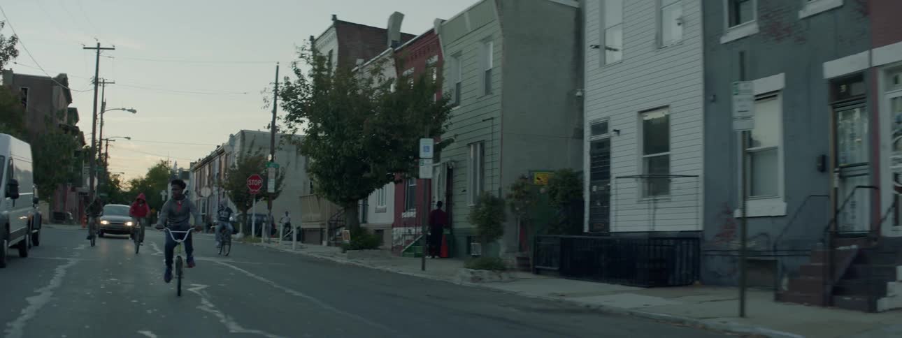 Three young men ride bikes down a street