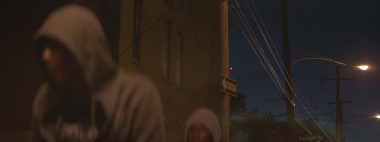 Two men in hoodies stand near a one way sign