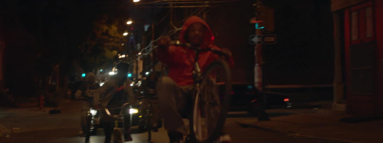 People ride their bikes down a street at night