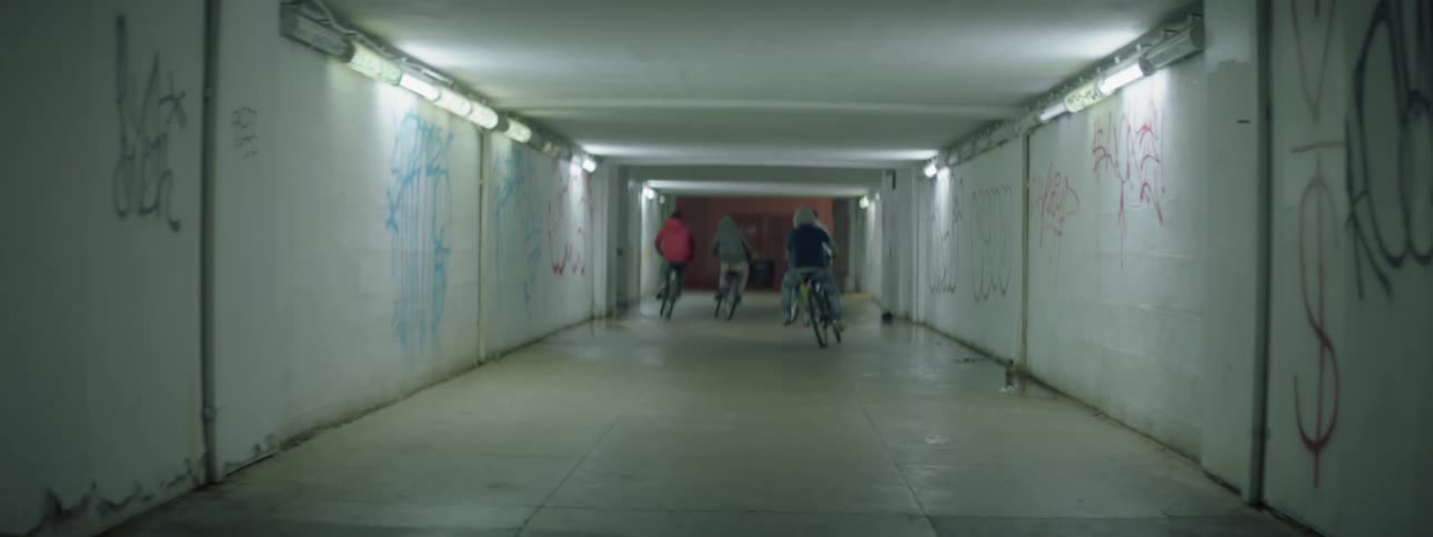 People riding their bikes down a lit up tunnel