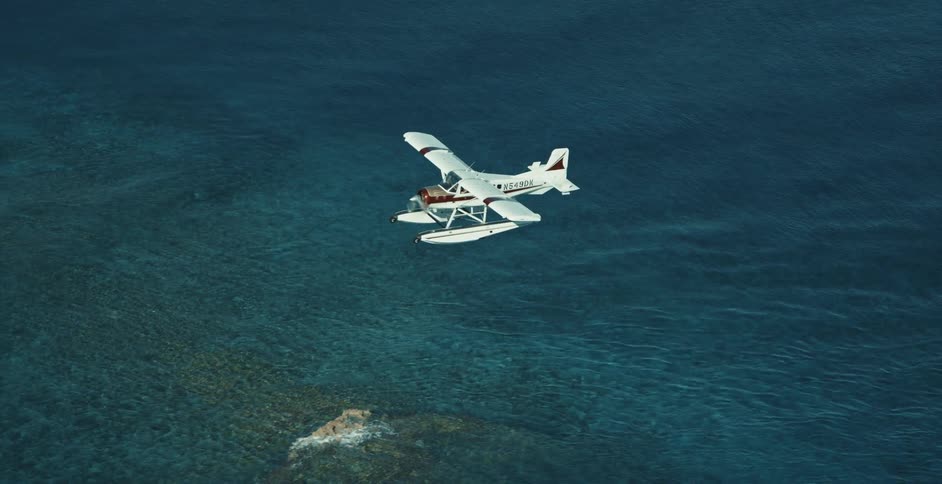 Seaplane flying low over calm blue sea and tiny islands approaching