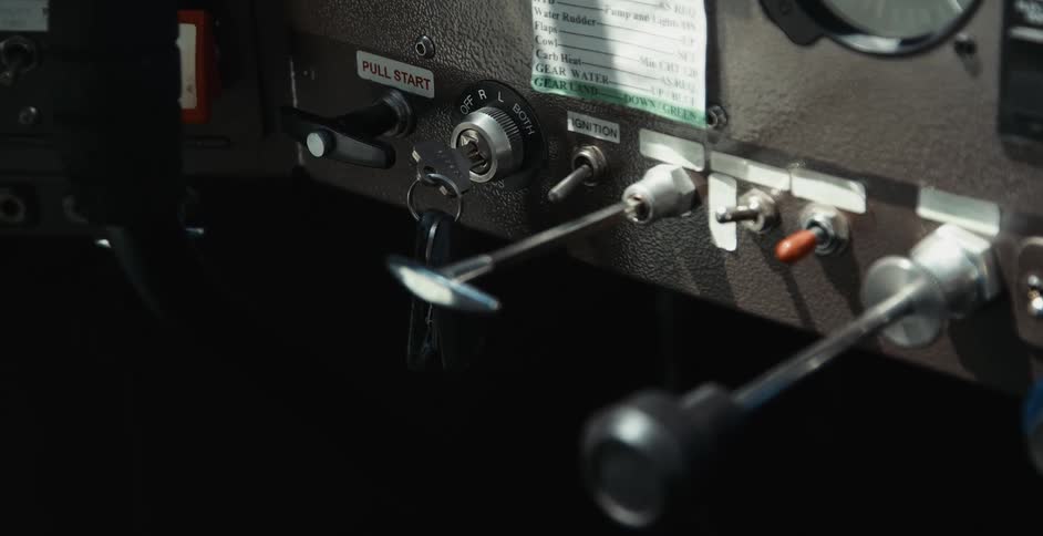 A close up of a vehicle dashboard with switches throttles and buttons and a key ignition