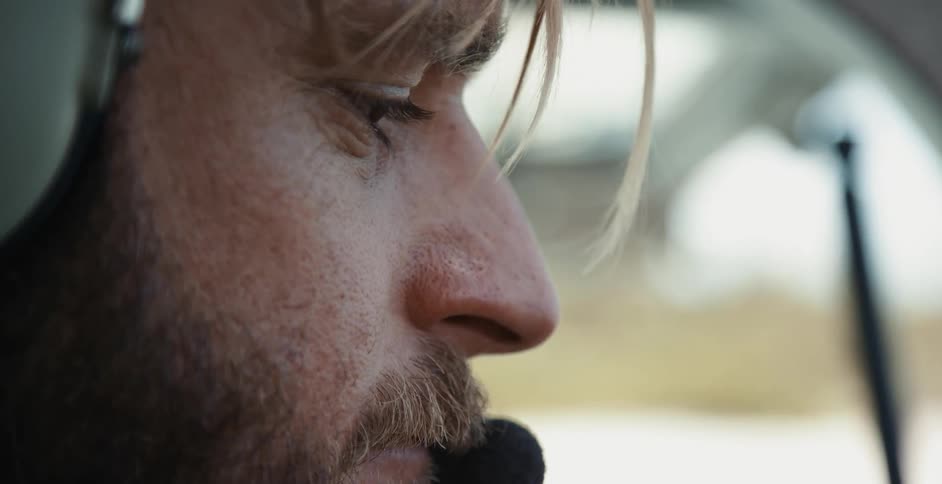 Close up of the face of a helicopter pilot wearing an aviation headset preparing for take off