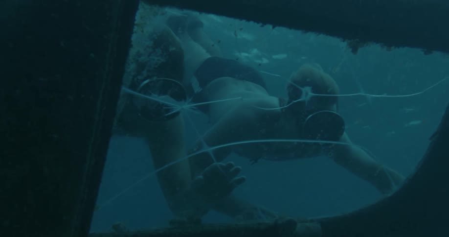 A pair of divers explore a shipwreck underwater