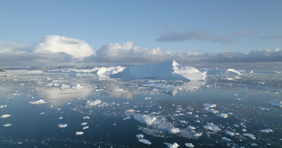 Moving across icy ocean waters with chunks of ice and glacier in the distance