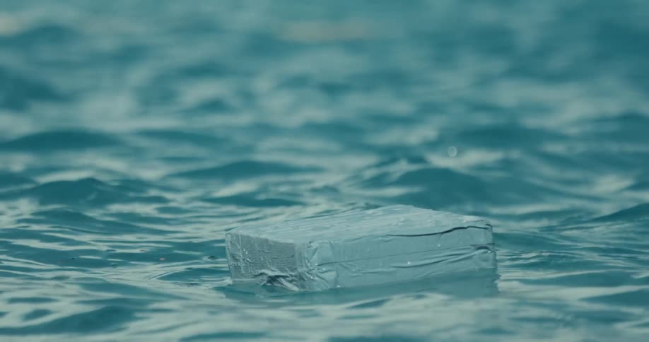 A blue package floating in the ocean water moving with the waves