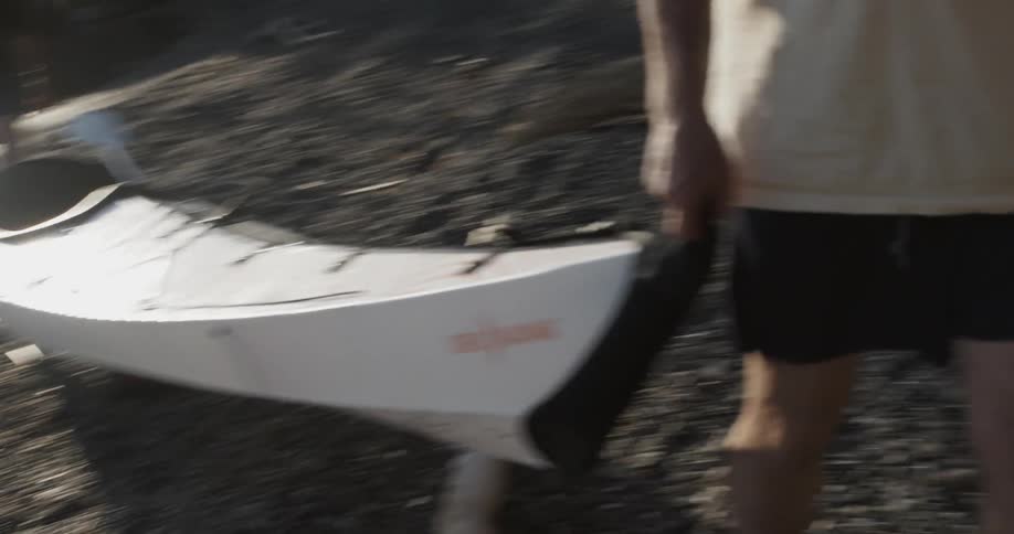 Two men pull a kayak onto the beach