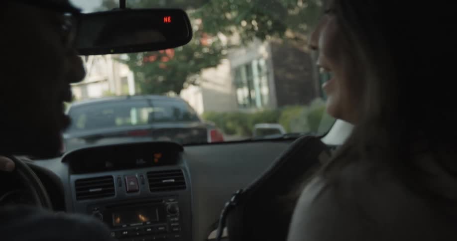 A woman gets into a car and is kissed by a male