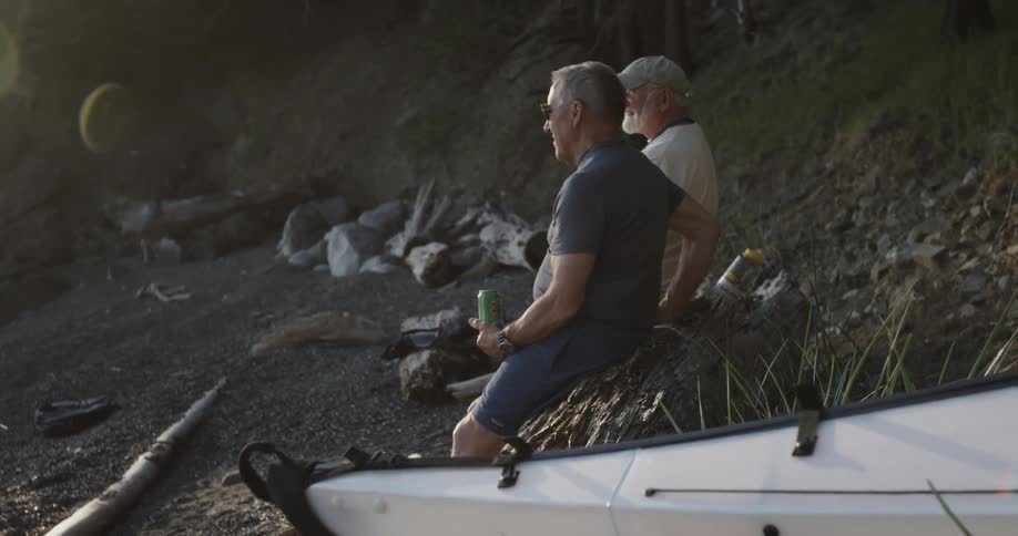 Two men chatting and resting on a large piece of driftwood