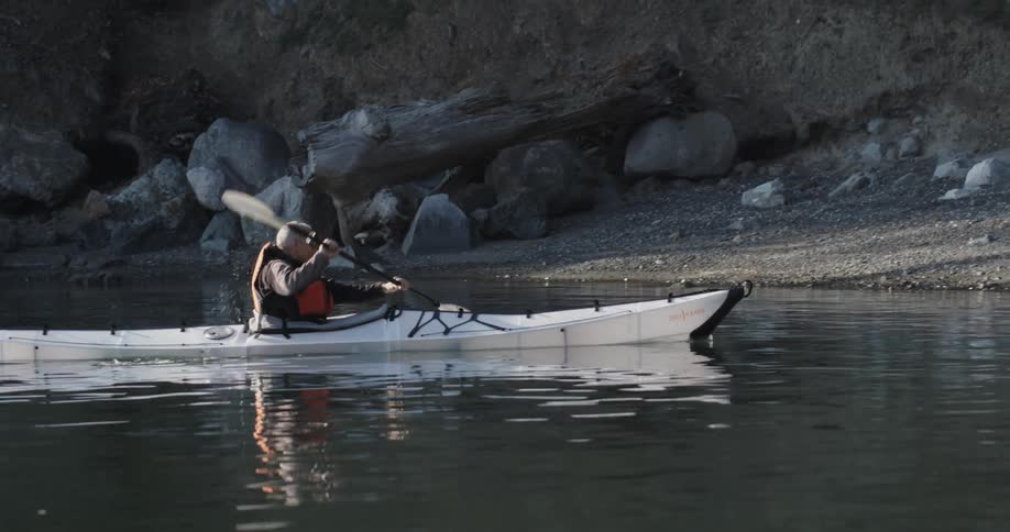 An older man rows a kayak toward shore