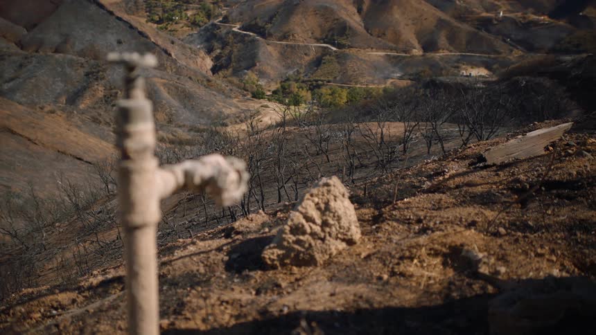 An outdoor spicket for water and desert mountain valleys in the distance
