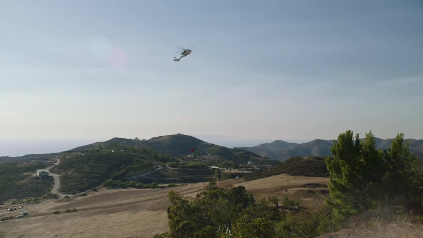 The helicopter descends by the mountains