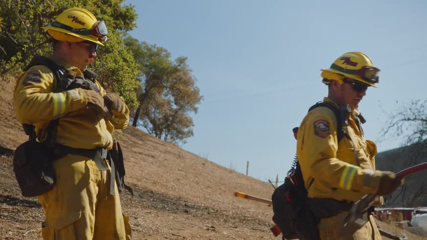 Firefighters retracting a hose to the firetruck