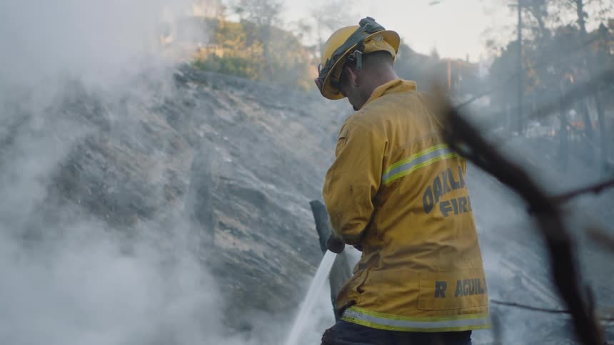 A firefighter using a hose to spray the ground as it steams
