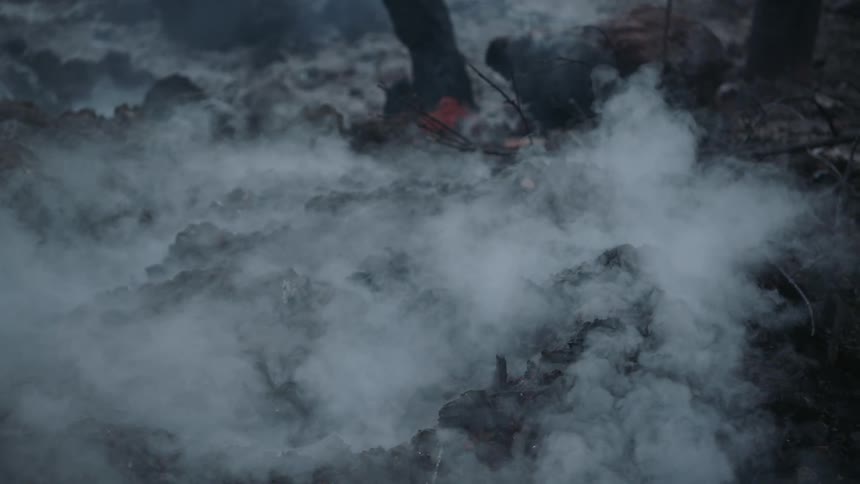 Smoke rises from hot charred ground burnt by wildfire